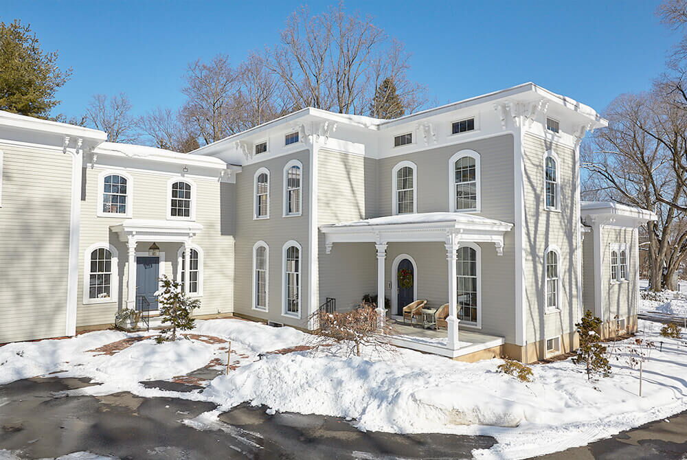 Exterior view of off-white house with snow surrounding