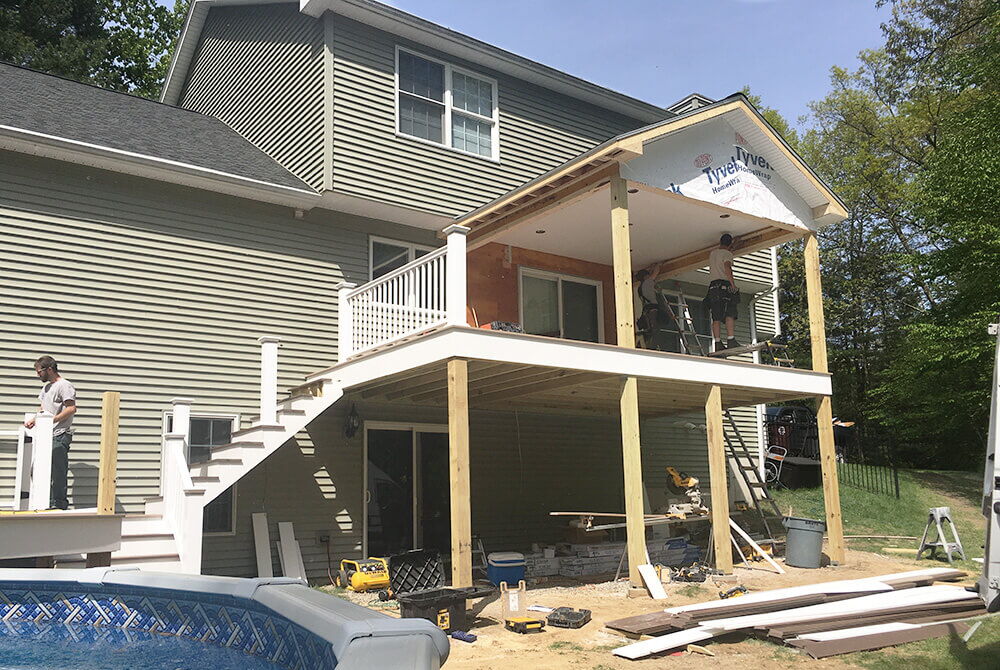 exterior view of partially finished sunroom with stairs leading to above ground pool
