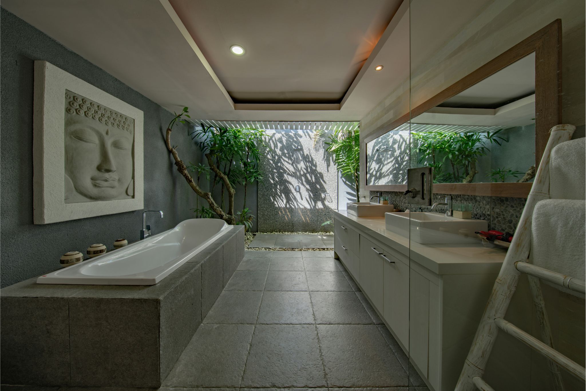 Spa-style bathroom with soaking tub, natural stone, and lush indoor-outdoor greenery.